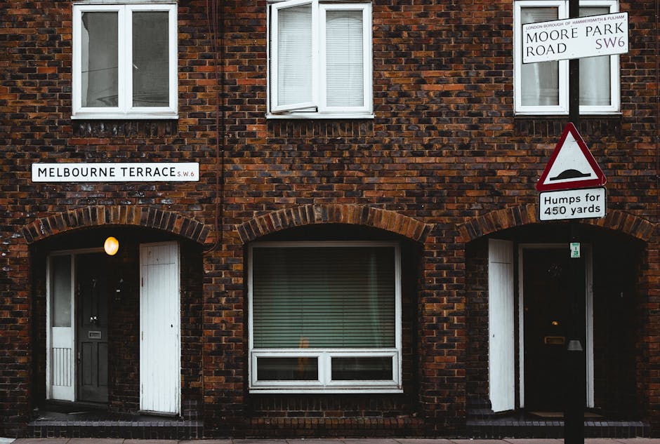 Two removal personnel are engaged in the loading process outside a commercial premises on Fulham Road, Brompton, during a house or business relocation operated by Removals Brompton. One worker is hold